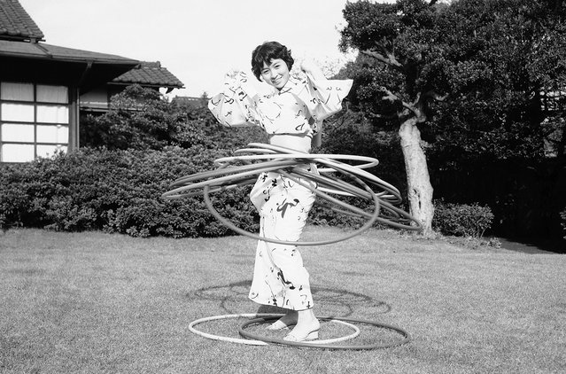 Seorang wanita muda Jepang dalam busana kimono tampak ikut terjangkit demam Hula-Hoop yang saat itu melanda Amerika dan Jepang, dalam foto bertanggal 30 Oktober 1958. (Photo by Mitsunori Chigita/AP Photo via The Atlantic)