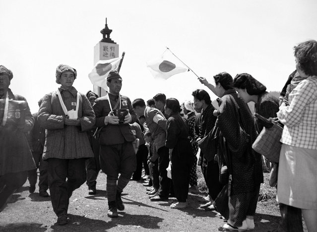 Para wanita menyambut rombongan tentara Jepang yang dipulangkan setelah menjadi tahanan perang, pada 26 April 1950. Para tentara ini tampak membawa abu rekan-rekan mereka yang tewas selama masa tahanan. (Photo by AP Photo via The Atlantic)