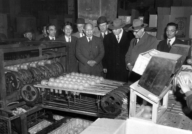 Para ahli pelatihan industri mengawasi sebuah mesin bola lampu menjatuhkan bohlam pada pekerja lain yang menyortirnya berdasarkan cacat atau kerusakan bohlam tersebut, di Tokyo Shibaura Electric Co. , kota Tokyo, 25 Januari 1951. (Photo by Arthur Curlis/AP Photo/U.S. Army via The Atlantic)