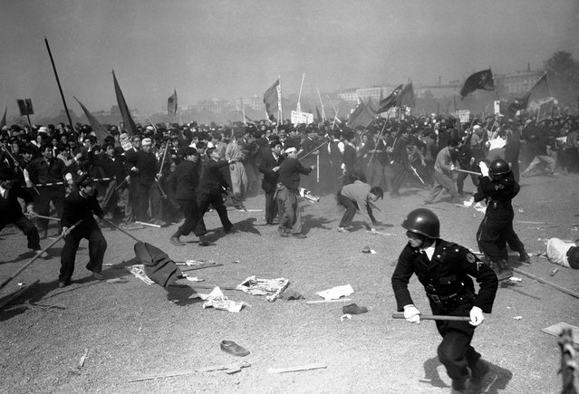 Para demonstran pro-komunis melempari polisi Jepang dengan batu pada kerusuhan "May Day" di Tokyo pada 1 Mei 1952. Korban berjatuhan dari kedua pihak, polisi Jepang menggunakan gas air mata, senapan, dan pentungan untuk memukul mundur para perusuh. (Photo by Max Desfor/AP Photo via The Atlantic)