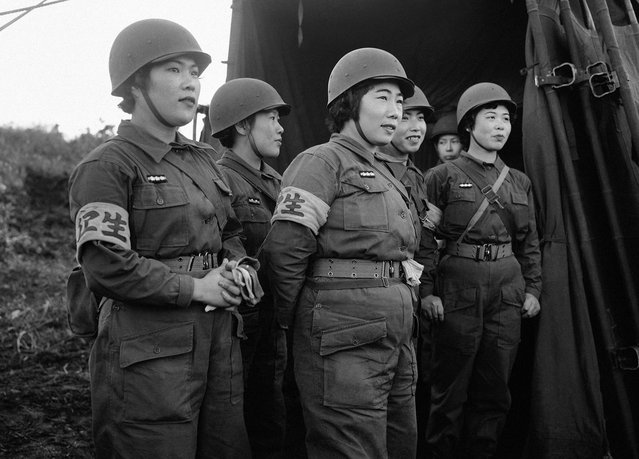 Para wanita perawat dari pasukan Bela Diri Jepang yang baru dibentuk, di Hokkaido, Jepang, dalam sebuah latihan perang pada 20 Oktober 1955. Pasukan Jepang, menggunakan peralatan yang disuplai oleh Amerika Serikat melakukan latihan militer pertama kalinya setelah perang dunia dengan sebuah kelompok pengawas dari Amerika Serikat dan pengawas militer dari negara asing lainnya, dalam sebuah skenario pertahanan melawan "musuh bayangan" yang menginvasi kepulauan Jepang. (Photo by AP Photo via The Atlantic)