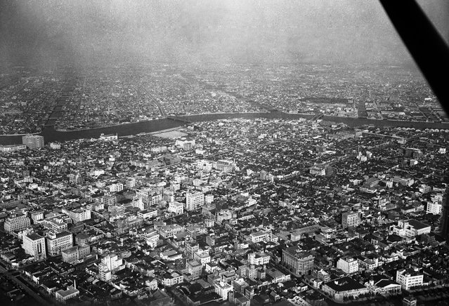 Sebuah area di Tokyo, terlihat dari langit pada 5 Agustus 1955. Bangunan-bangunan modern telah menghapus bekas reruntuhan blok-blok yang telah diratakan dengan tanah. Sungai Sumida mengalir dengan damai melalui distrik Hamacho dan distrik Fukawaga. Rumah-rumah grosir dan gudang-gudang memenuhi sebagian besar distrik ini. (Photo by AP Photo via The Atlantic)