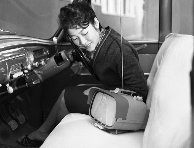 Tomiko Kawabata duduk di dalam mobilnya mengagumi televisi transistor terbarunya yang portabel, yang diproduksi secara masal oleh Sony, di Tokyo, 5 Januari 1960. Televisi yang memiliki layar delapan inchi ini dilengkapi baterai yang sanggup bertahan tiga jam ketika digunakan diluar ruangan, dan juga bisa beroperasi tanpa baterai dengan menggunakan listrik 200 V dalam ruangan. (Photo by AP Photo via The Atlantic) 